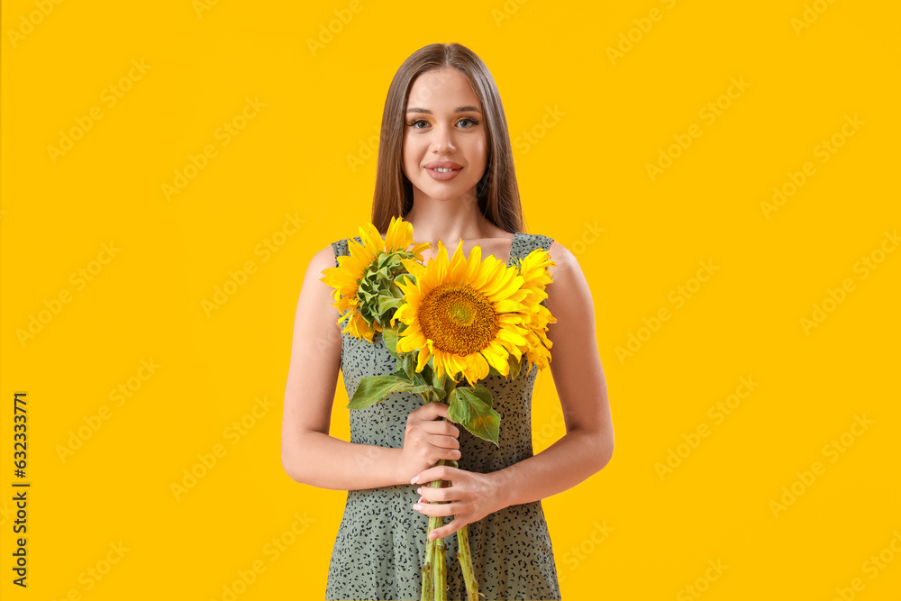 Young happy woman with bouquet of beautiful sunflowers on yellow background