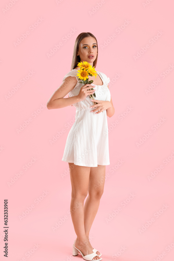 Young woman with bouquet of beautiful sunflowers on pink background