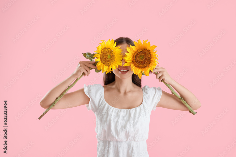 Young happy woman with beautiful aroma sunflowers on pink background