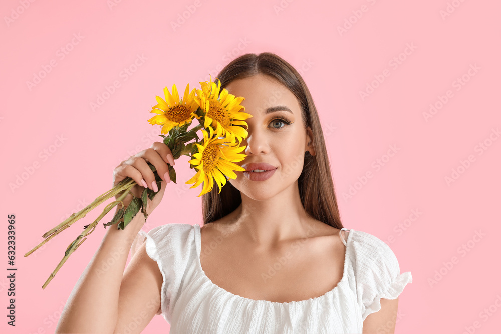 Young woman with bouquet of beautiful sunflowers on pink background