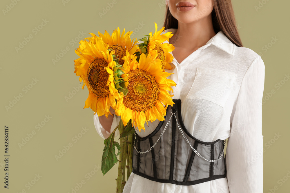 Young woman with bouquet of beautiful sunflowers on green background