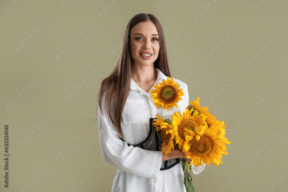 Young happy woman with bouquet of beautiful sunflowers on green background