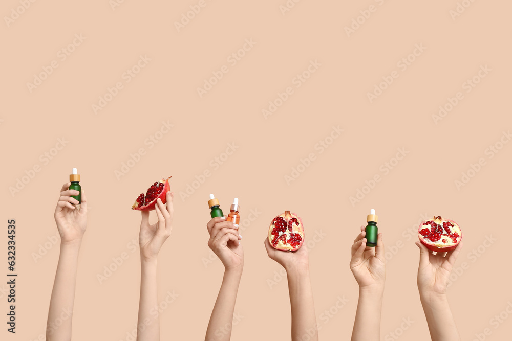 Female hands holding cosmetic products and pomegranate on beige background