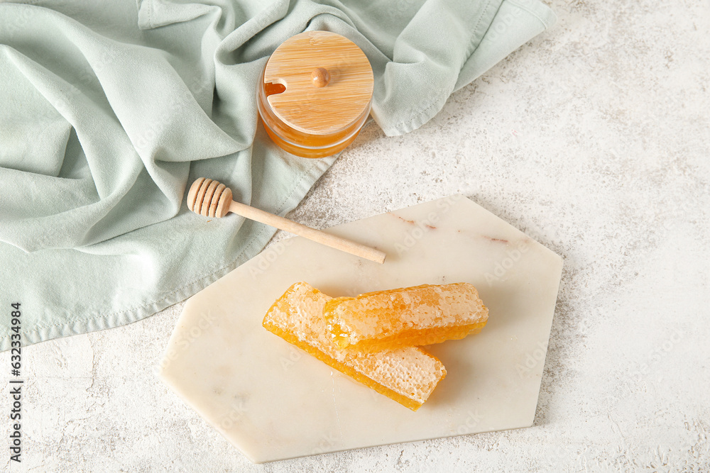 Jar of sweet honey, combs and dipper on light background