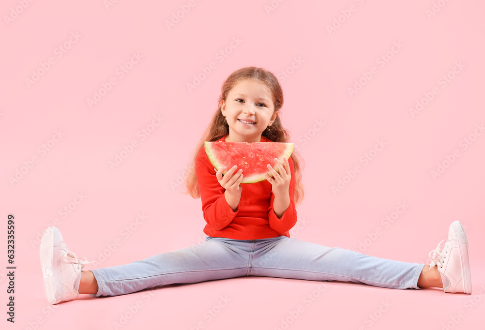 Happy little girl with slice of fresh watermelon sitting on pink background