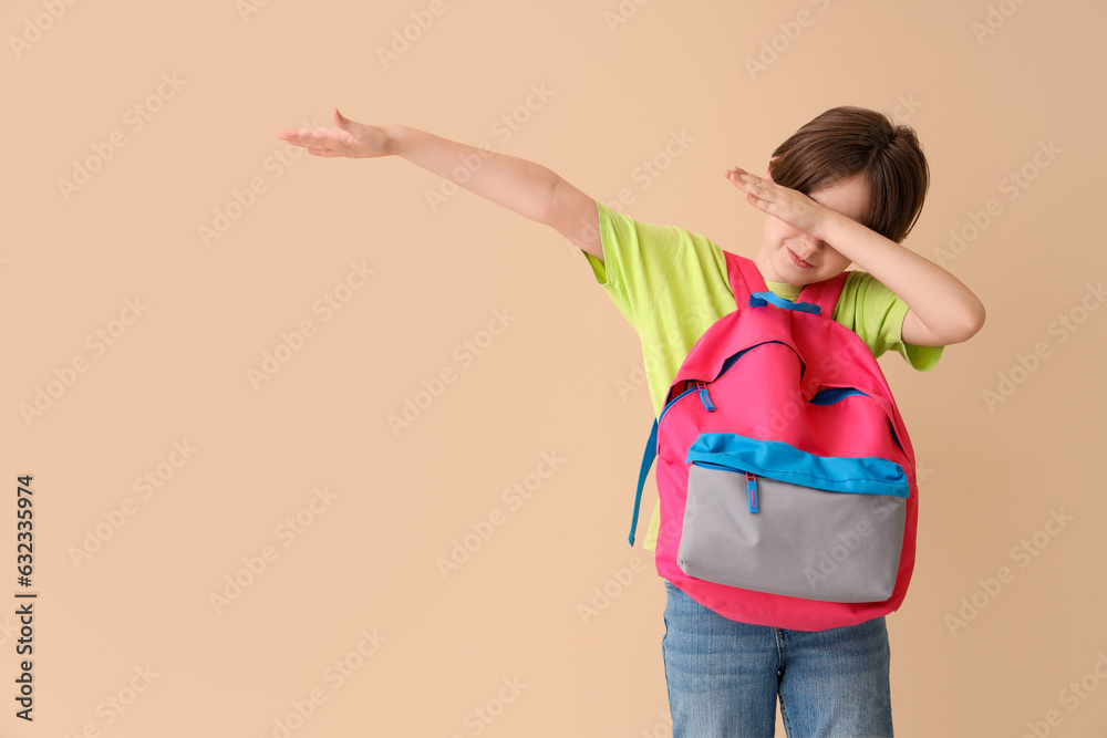 Little boy with backpack on beige background