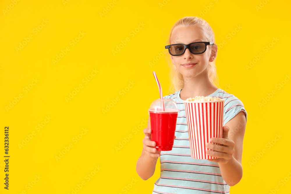 Cute girl in 3D cinema glasses with bucket of popcorn and cola on yellow background