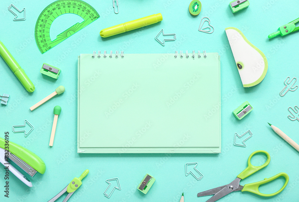 Notebook with different stationery supplies on turquoise background