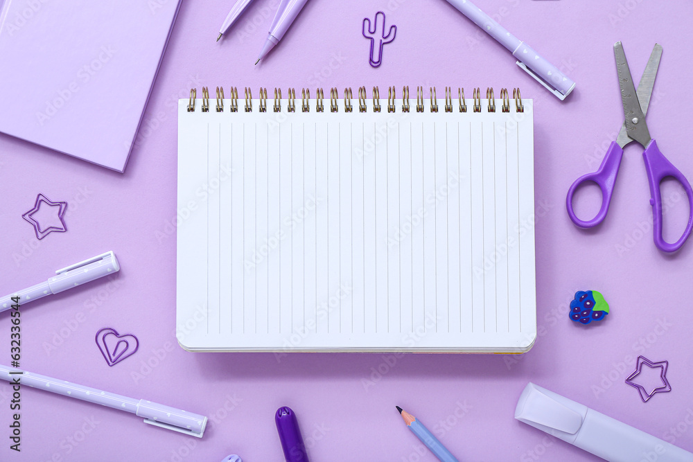 Notebook with different stationery supplies on lilac background