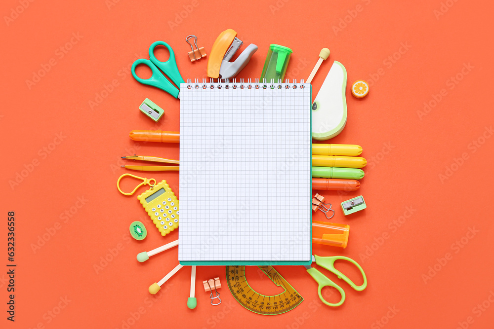 Notebook with different stationery supplies on orange background