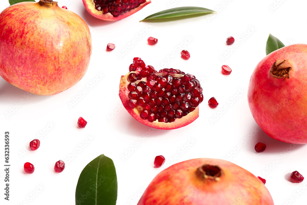 Fresh pomegranates with seeds and leaves on white background