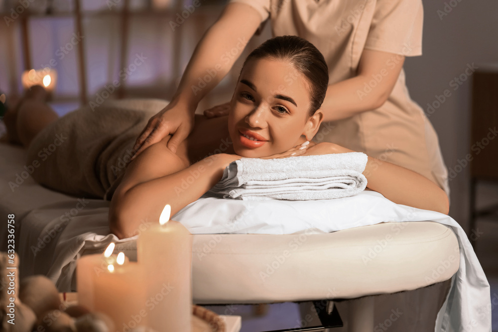 Pretty young woman having massage in spa salon