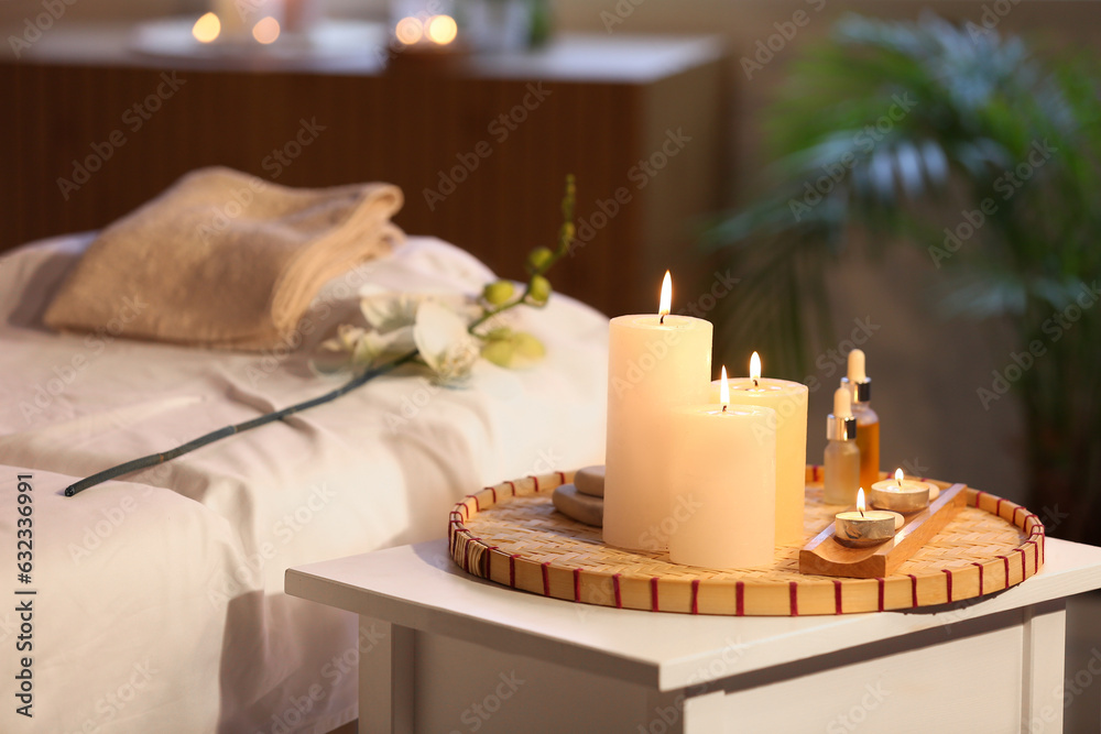 Burning candles and essential oil on table in spa salon