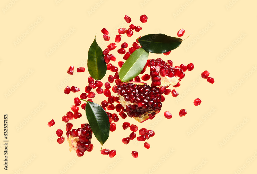 Flying fresh pomegranates with seeds and leaves on orange background