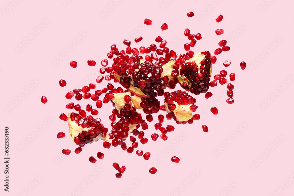 Flying fresh pomegranate with seeds on pink background