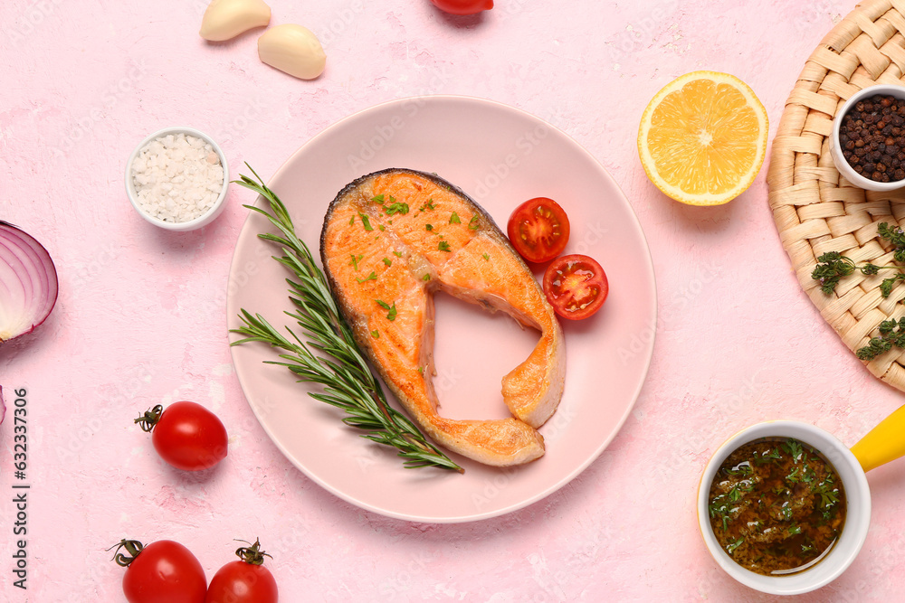 Plate of tasty salmon steak with tomatoes and lemon on pink background