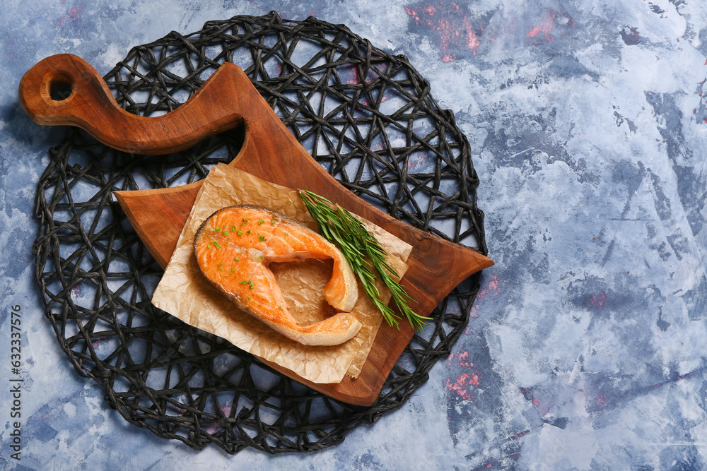 Wooden board of tasty salmon steak on blue background