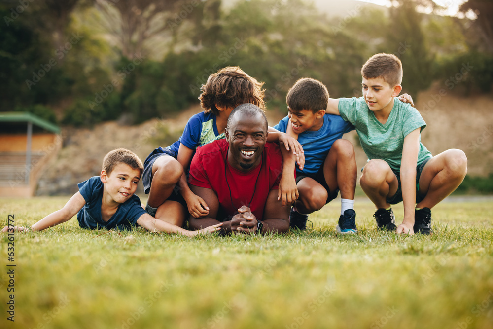 School coach and his team lying in a sports field