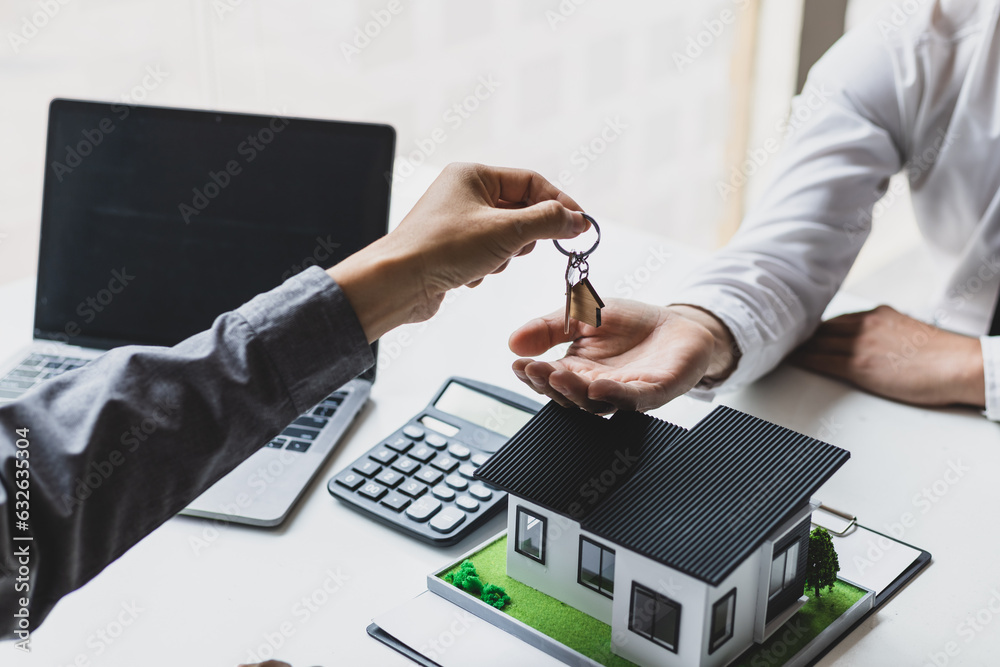 Real estate agent hands over the house keys to a homebuyer after the purchase agreement has been sig