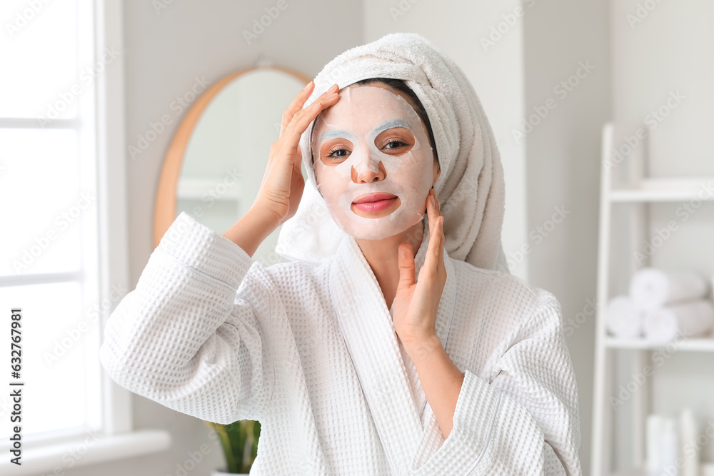 Young woman with sheet mask in bathroom