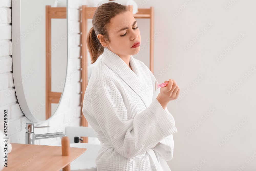 Upset young woman with razor in bathroom