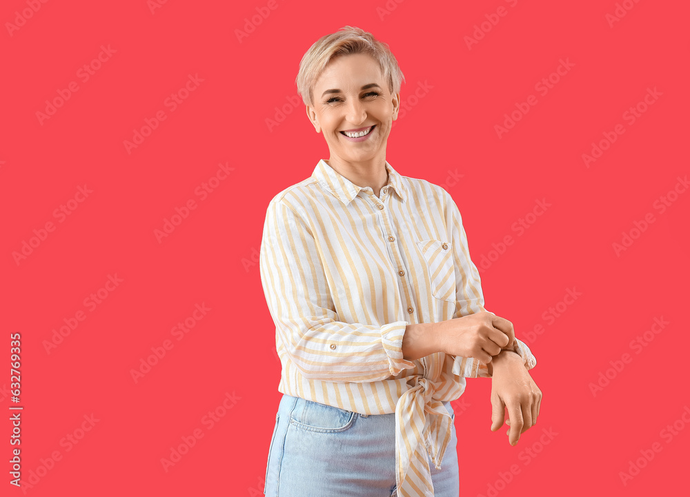 Mature woman rolling up her sleeve on red background