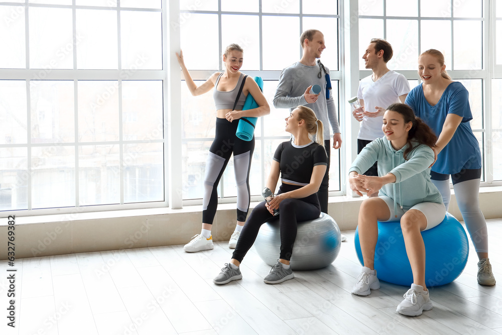 Group of sporty young people with bottles of water and equipment in gym