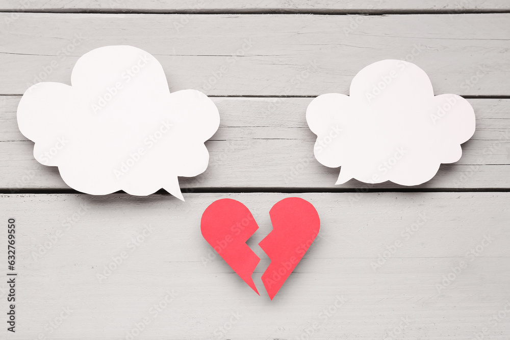 Broken heart with blank speech bubbles on grey wooden background