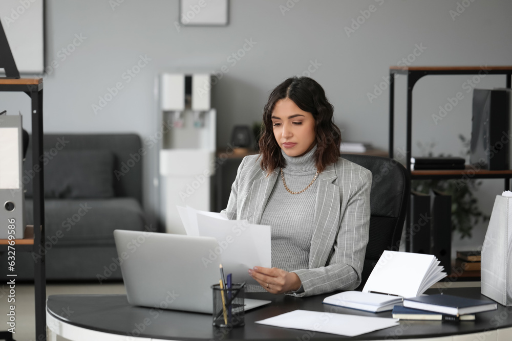 Young pregnant woman working with documents at table in office