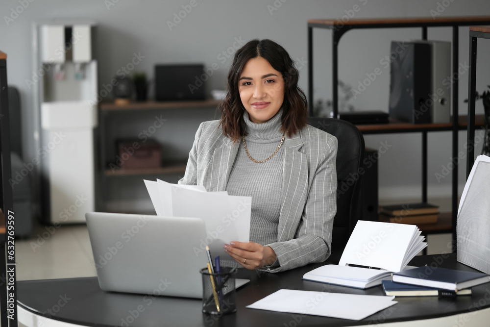 Young pregnant woman working with documents at table in office