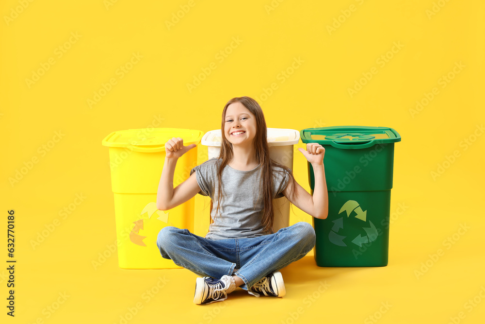 Little girl pointing at recycle trash bins on yellow background