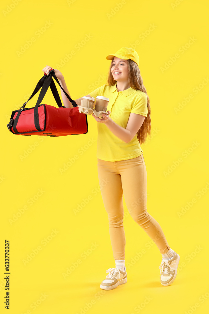 Female courier with thermal bag and cups on yellow background