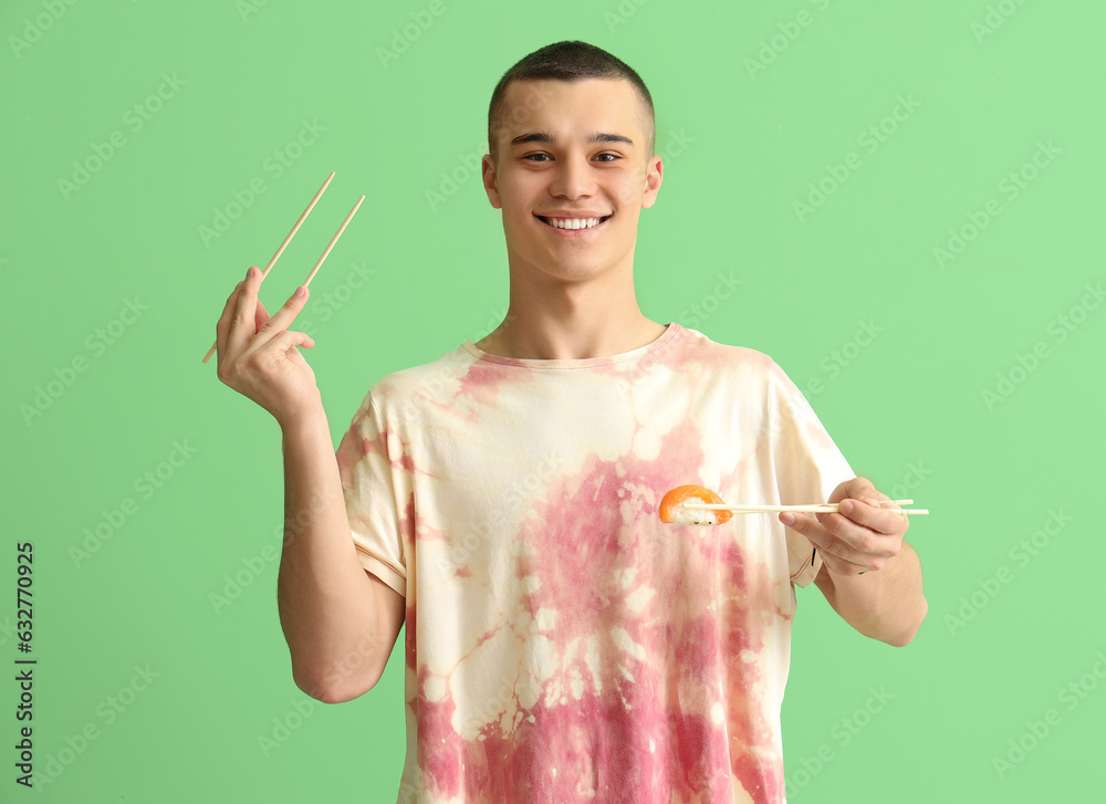 Young man with tasty sushi on green background