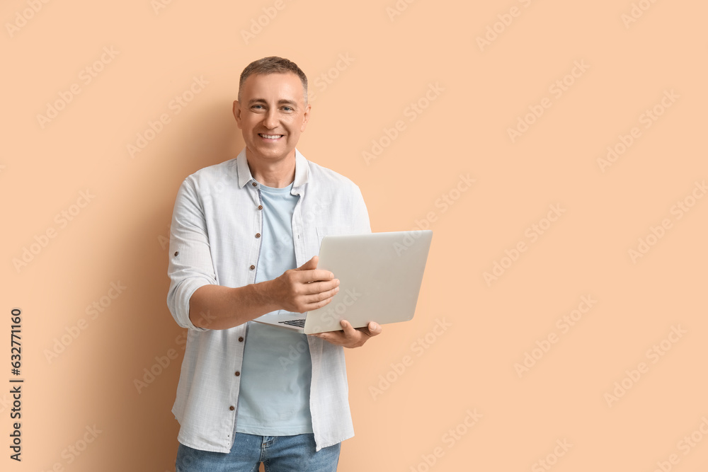 Mature male programmer with laptop on beige background