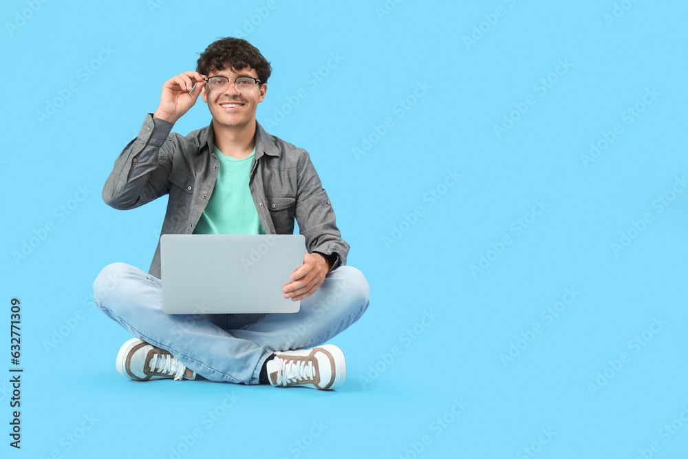 Male programmer working with laptop on blue background