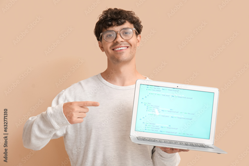 Male programmer pointing at laptop on beige background