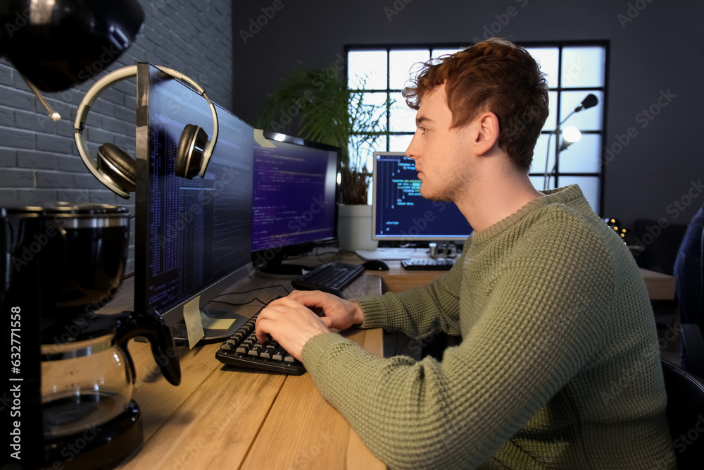 Male programmer working with computer in office at night