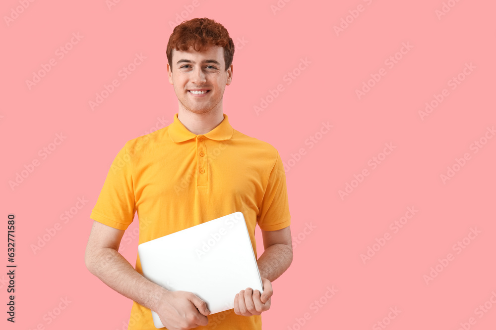 Male programmer with laptop on pink background