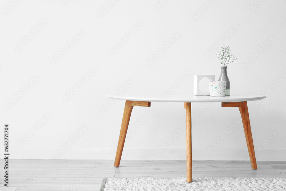 Gypsophila flowers and candle on table near light wall in room