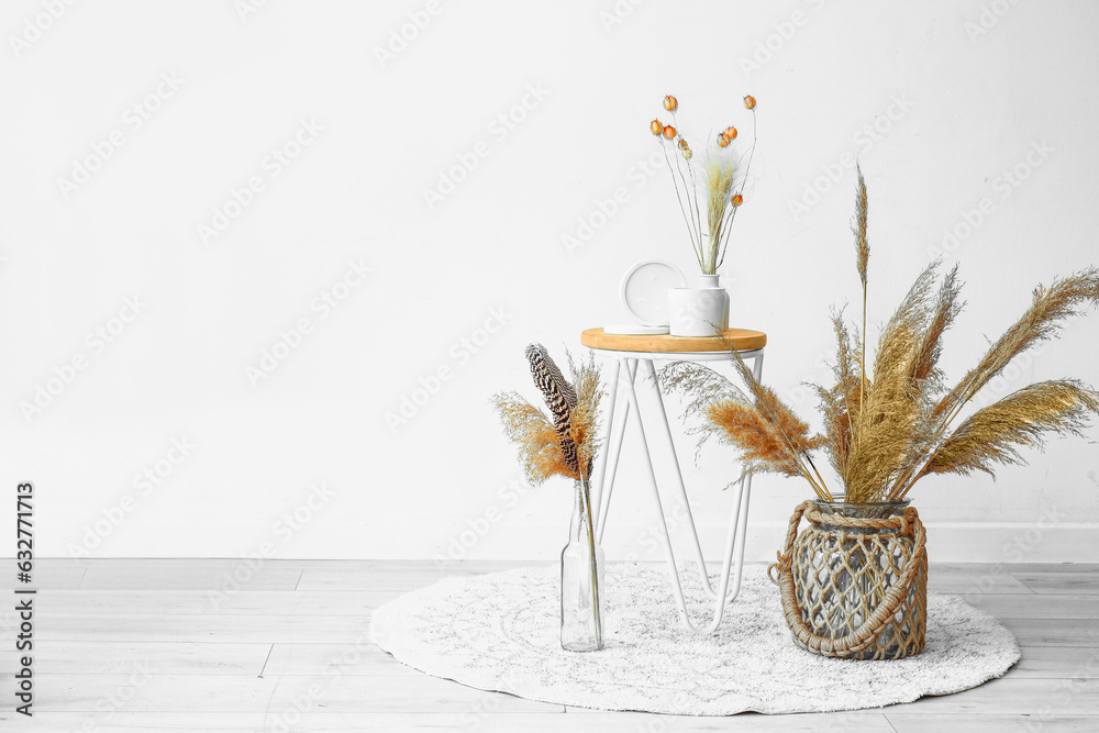 Interior of light room with candles, dried flowers on table and pampas grass