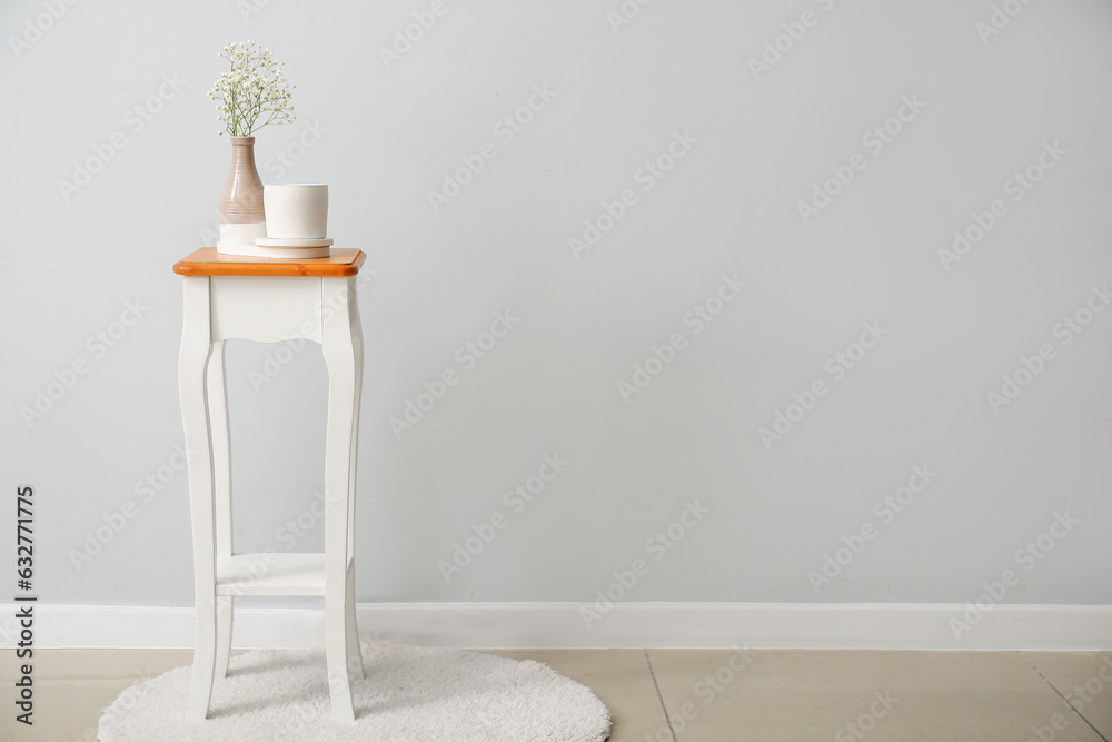 Gypsophila flowers and candle on chair near light wall in room