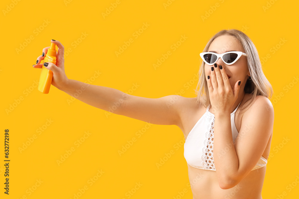 Young woman with sunscreen cream on yellow background