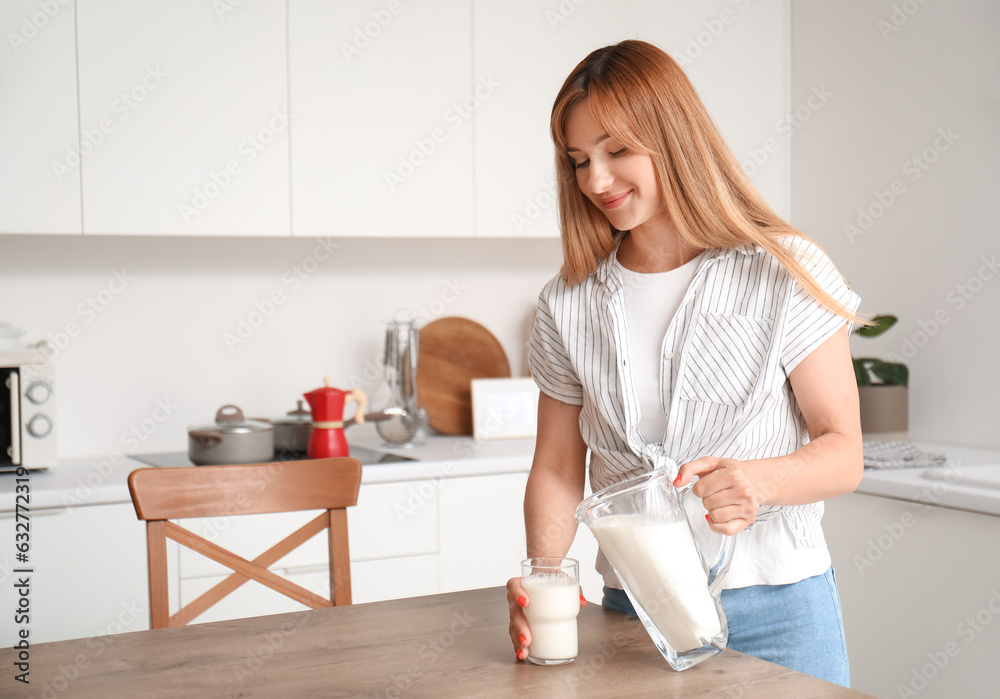 Young woman pouring milk into glass in kitchen