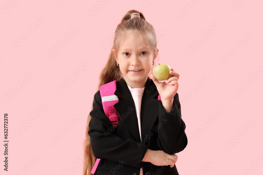 Little schoolgirl with apple on pink background