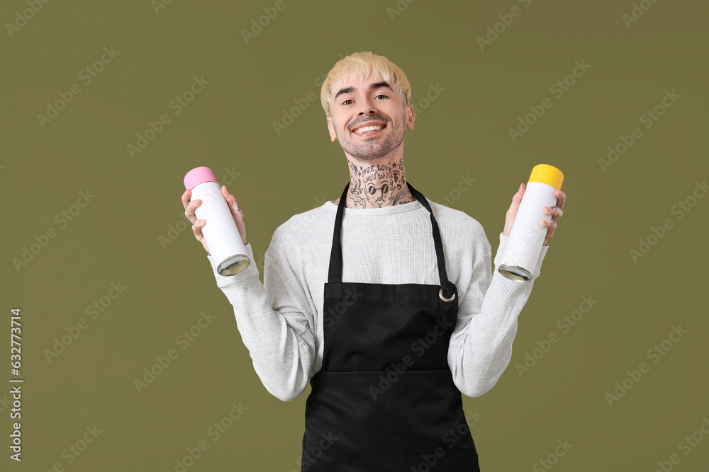 Young tattooed man with air fresheners on green background