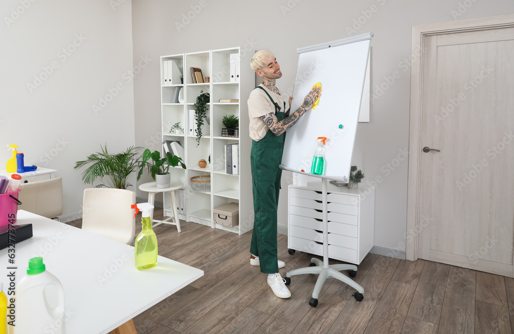 Male janitor cleaning flipboard in office