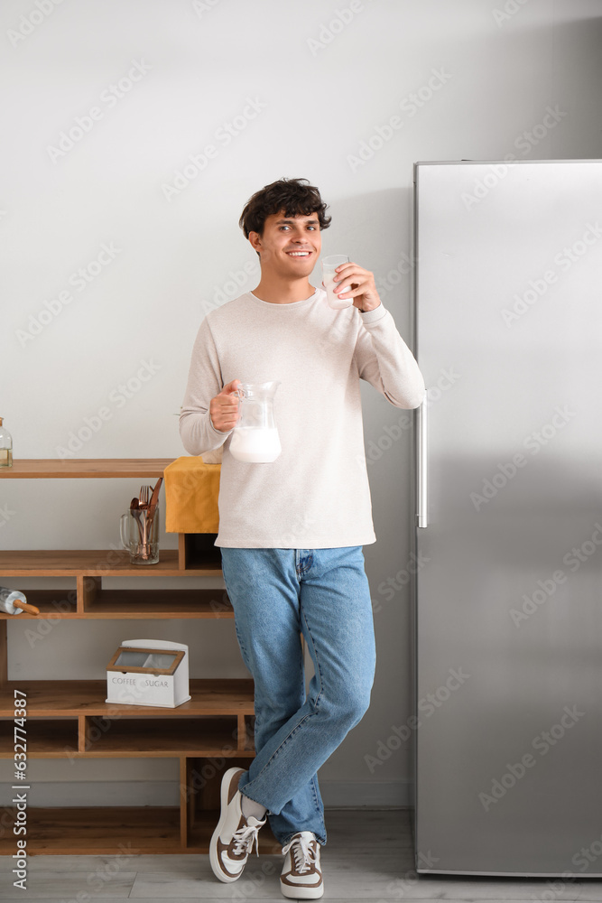 Young man drinking fresh milk in kitchen