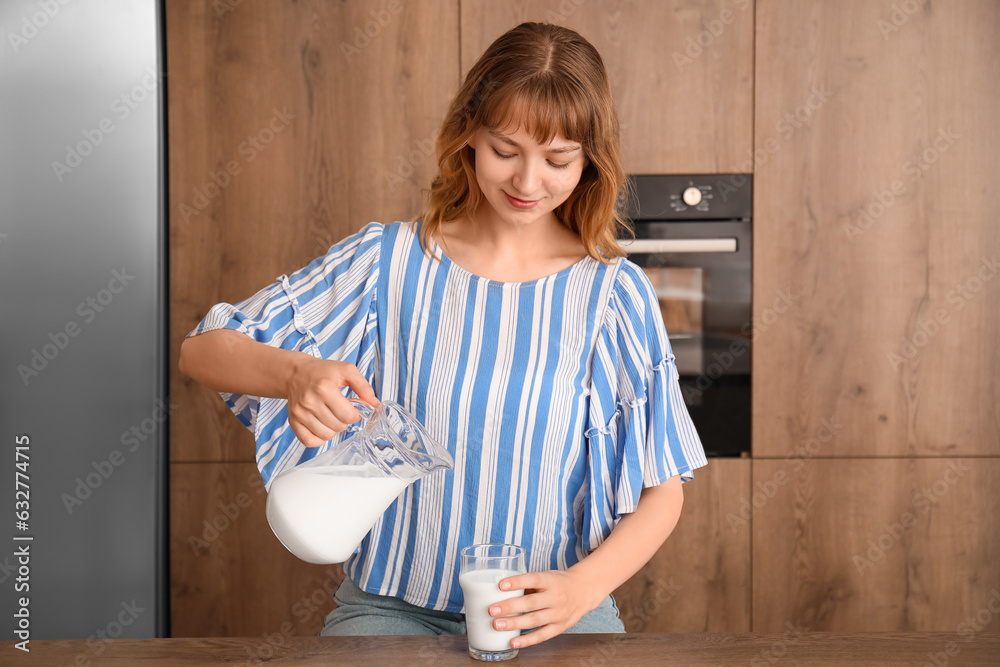 Young woman pouring milk into glass in kitchen