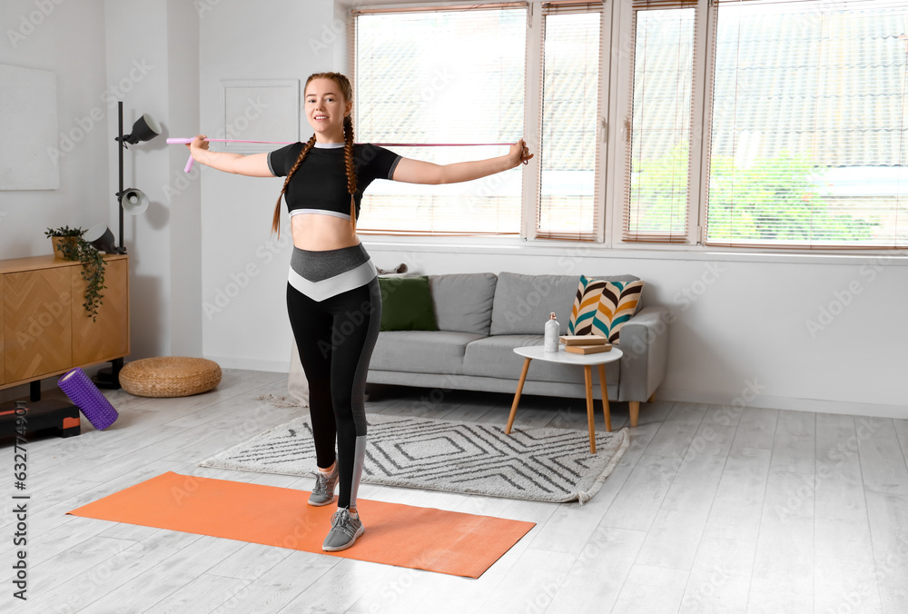 Sporty young woman stretching with rope at home