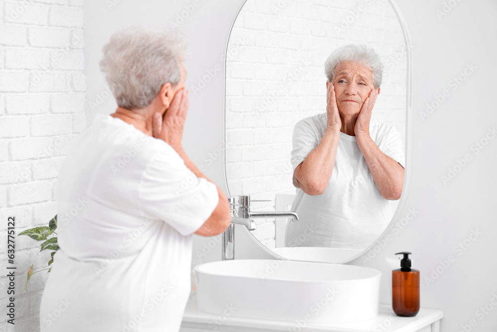 Senior woman looking in mirror at home